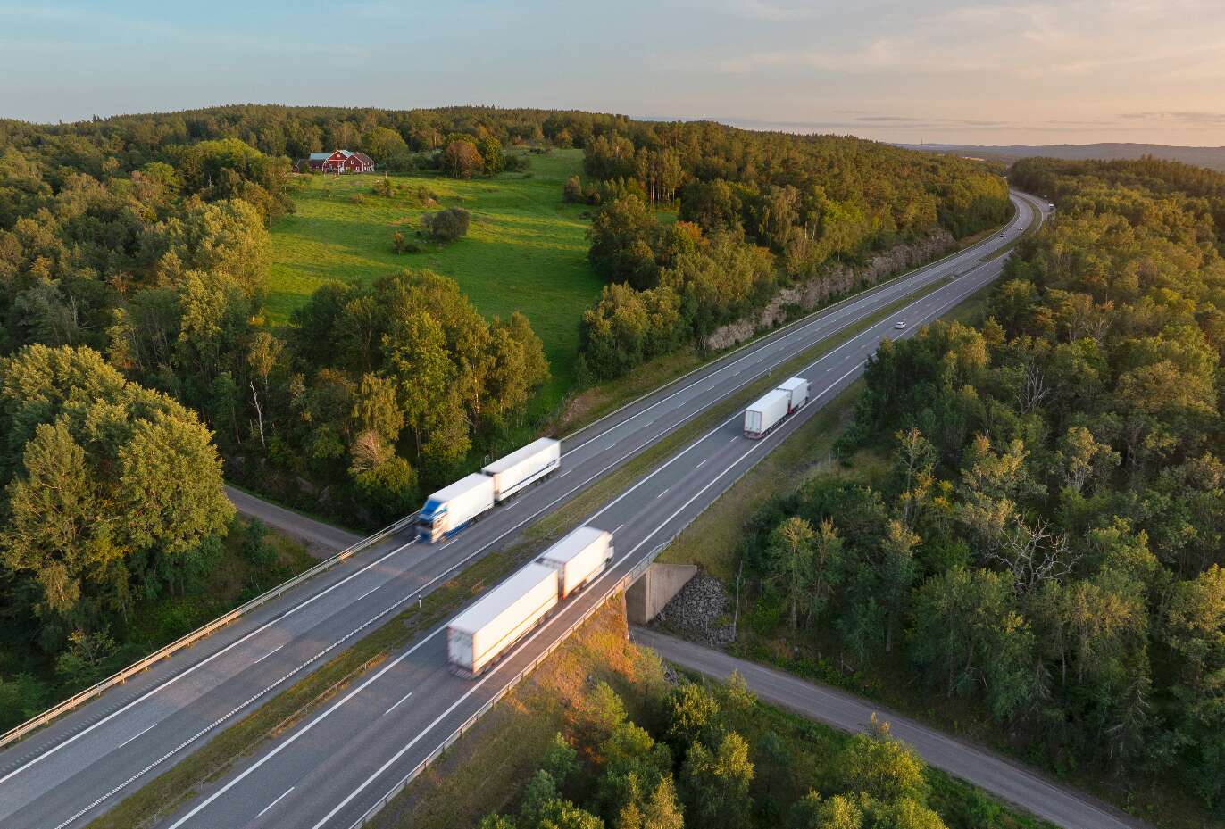 Lastbilar på landsväg i kvällsljus